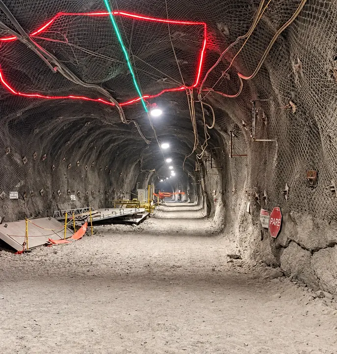 Túnel de mina subterránea iluminado, con malla de fortificación en el techo