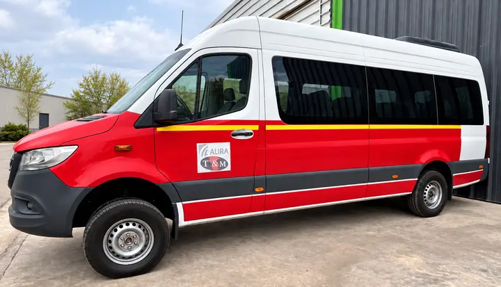 Minibús Sprinter rojo y blanco de costado, con el logo de T&M en la puerta